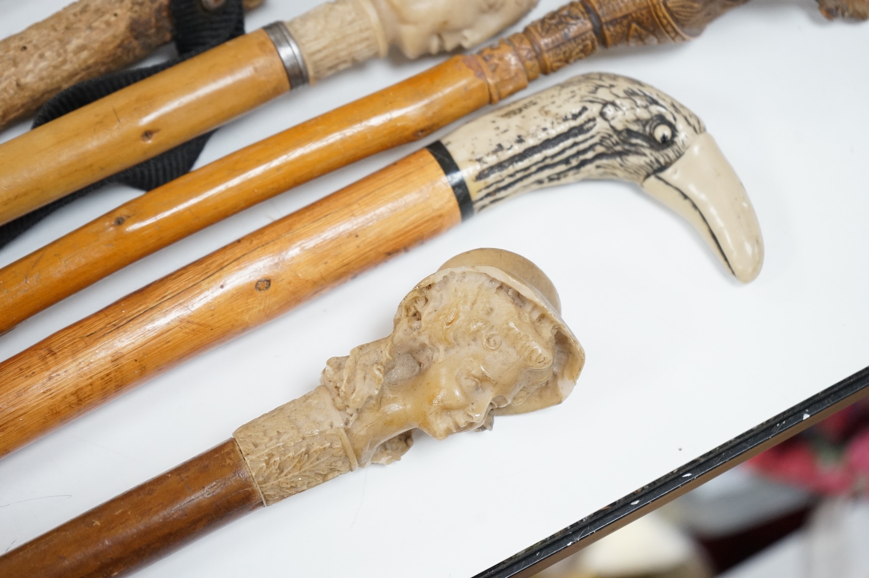 A collection of eight mostly moulded resin mounted walking canes to include one in the form of a lizard, largest 93cm in length